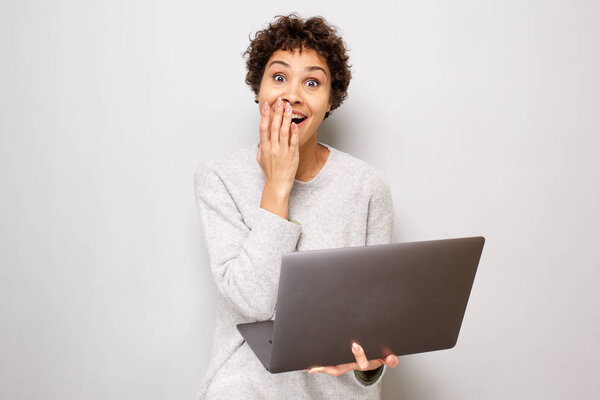 Портрет удивленной молодой африканской женщины с ноутбуком
