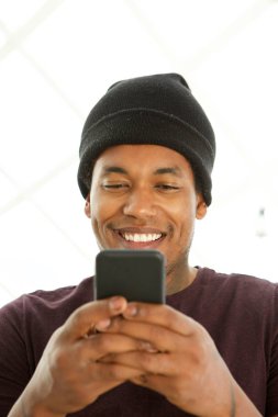 Cep telefonu bakarak gülümseyen Afro-Amerikan adam yakın portresi 