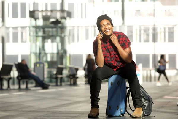Portret Szczęśliwego Młodego Czarnego Mężczyzny Podróży Siedzącego Walizki Podczas Rozmowy — Zdjęcie stockowe