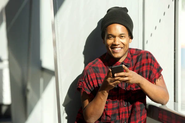 携帯電話を持ち 微笑むクールな若い黒人男性の肖像画 — ストック写真