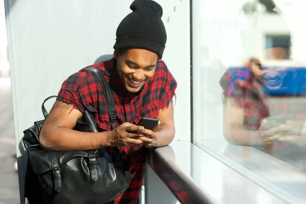 Portret Szczęśliwego Młodego Czarnego Mężczyzny Torbą Patrząc Telefon Komórkowy — Zdjęcie stockowe