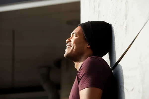 壁に寄りかかって微笑むハンサムな若いアフリカ系アメリカ人男性のクローズアップサイドポートレート — ストック写真