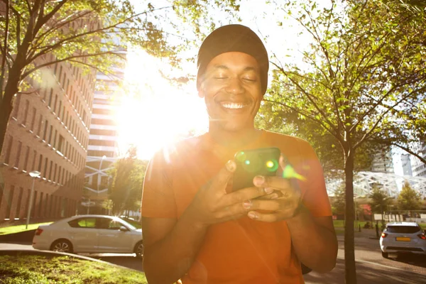 Portret Uśmiechnięty African American Man Chodzenie Mieście Telefonem Komórkowym Słoneczny — Zdjęcie stockowe