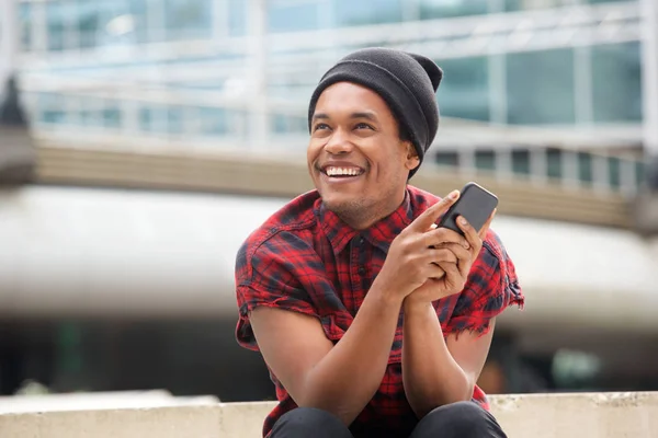 Retrato Joven Negro Feliz Con Gorro Sentado Afuera Ciudad Con — Foto de Stock