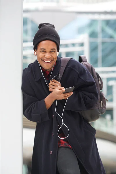 イヤホンや携帯電話で音楽を聴くクールな若いアフリカ系アメリカ人の肖像画 — ストック写真