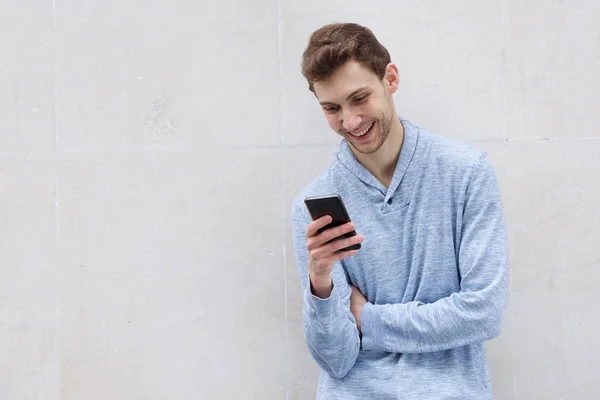 Portrét Usmívajícího Mladého Muže Který Dívá Mobilní Telefon Zdi — Stock fotografie