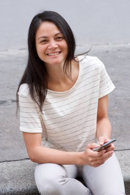 Cep telefonu açık havada gülümseyen Genç Asyalı kadının portresi