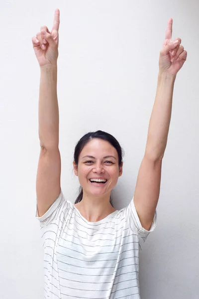 腕を上げて指を上げて笑う陽気なアジアの若い女性の肖像画 — ストック写真