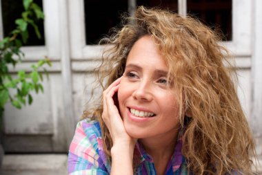 Kıvırcık sarı saçlı gülümseyen orta yaş kadın portre yakın