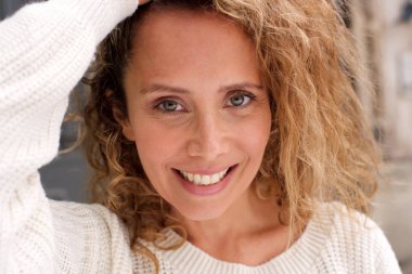 Kıvırcık saçlı el ile gülümseyen mutlu orta yaş kadının portre yakın