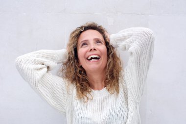 Beyaz arka plana karşı baş arkasında elleri ile neşeli orta yaş kadın portre yakın