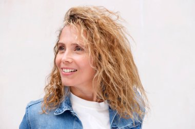 Beyaz duvara kıvırcık saçlı gülümseyen orta yaş kadın portre yakın yukarı 