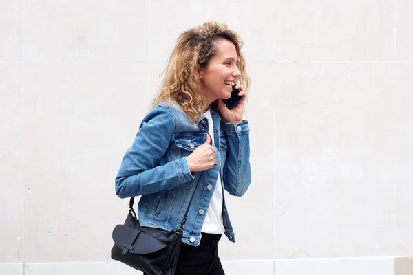 微笑的中年妇女步行和与手机在白色背景交谈的侧画 — 图库照片