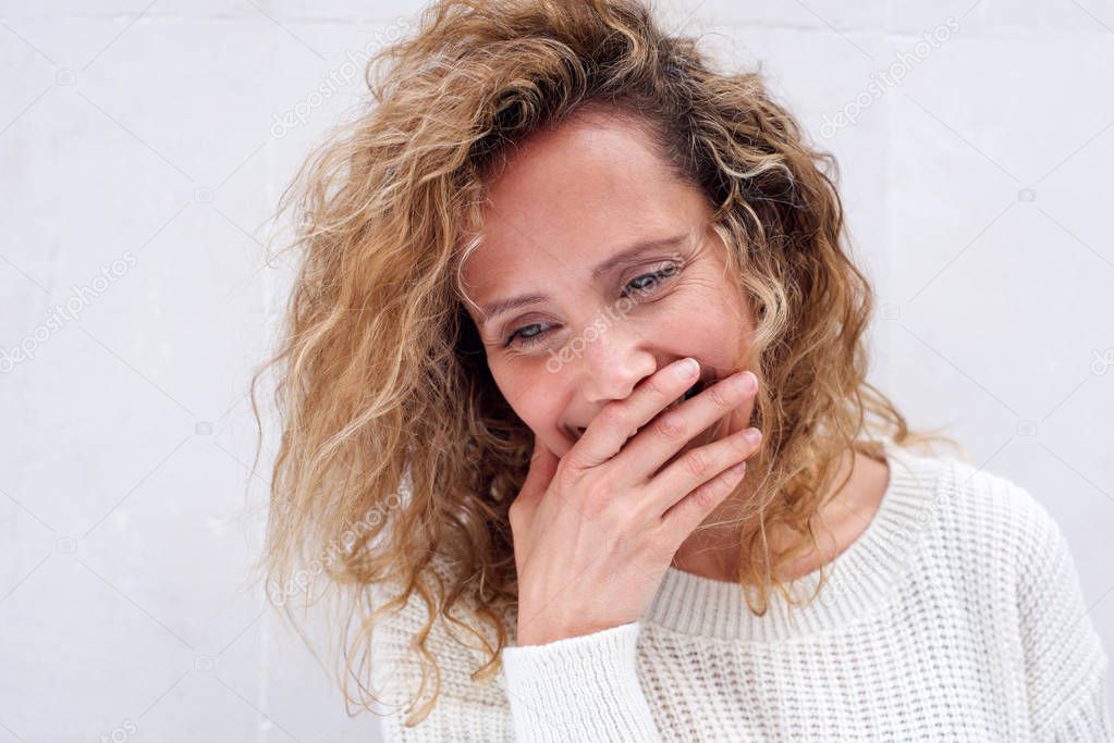 Close up portrait of happy middle age woman laughing with hand covering mouth