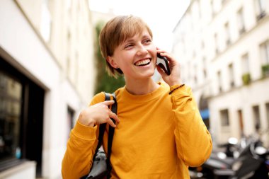 Şehirde yürüyen ve cep telefonu ile konuşan çanta ile genç kadının Portresi