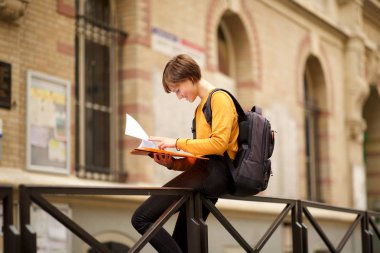 Kampüste kitap okuyan kız öğrencinin yan portresi