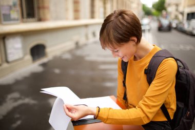 Üniversite öğrencisinin kampüste okuma kağıtları portresi