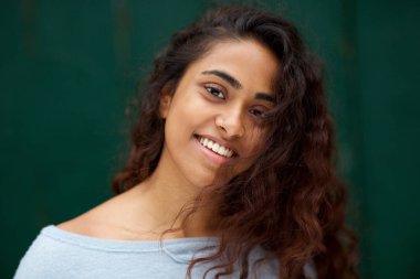 Yeşil arka plan karşı gülümseyen uzun saçlı güzel genç Hintli kadının yakın portresi