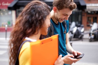 Şehirde cep telefonuna bakan mutlu öğrencilerin portresi