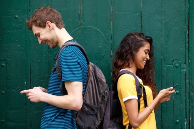 Arka arkaya dururken cep telefonuna bakan erkek ve kız öğrencilerin portresi