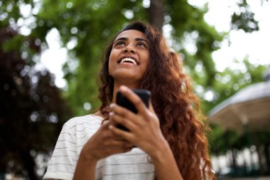 Cep telefonu tutan ve yukarı bakan mutlu genç kadın Portresi