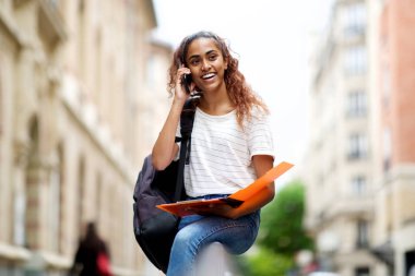 Cep telefonu ile konuşurken kolaj kampüsünde oturan genç kadının portresi