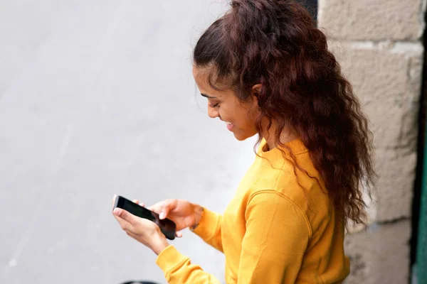 携帯電話を見ている幸せな若い女性のサイドポートレート — ストック写真