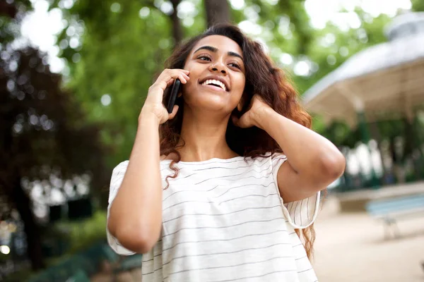 Close up portrait of young woman laughing and talking with mobile phone outdoors