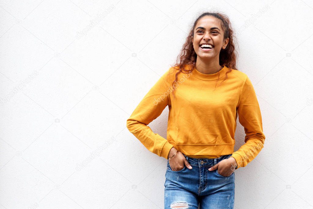 Portrait of beautiful young woman laughing by white wall