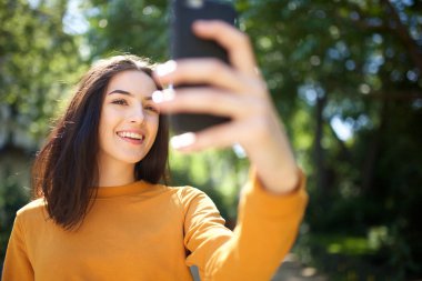 Selfie çekerken parkta gülen mutlu genç kadının portresi