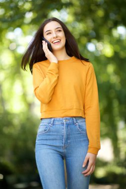 Parkta cep telefonu yla yürüyen güzel genç kadının portresi