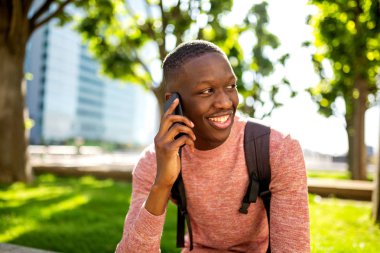 Şehir parkında cep telefonu ile konuşan genç siyah adamın portresi