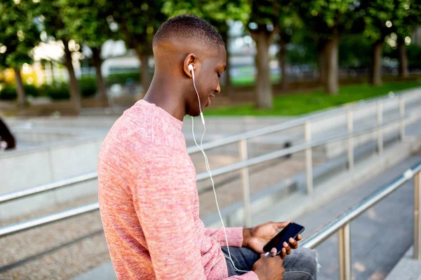 Boczny Portret Młodego Afrykańskiego Amerykanina Słuchający Muzyki Słuchawkami Telefonem Komórkowym — Zdjęcie stockowe