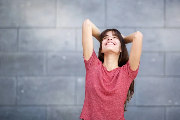 灰色の背景に対して頭の後ろに手で笑う陽気な若い女性の肖像画 — ストック写真