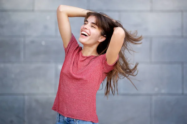 灰色の背景で頭の後ろで手で笑う陽気な若い女性の肖像画 — ストック写真
