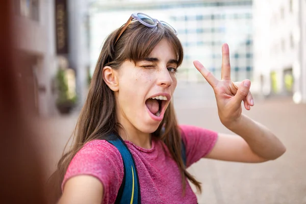 拍一张年轻女子拿着手机自拍的笑容可亲的画像 — 图库照片