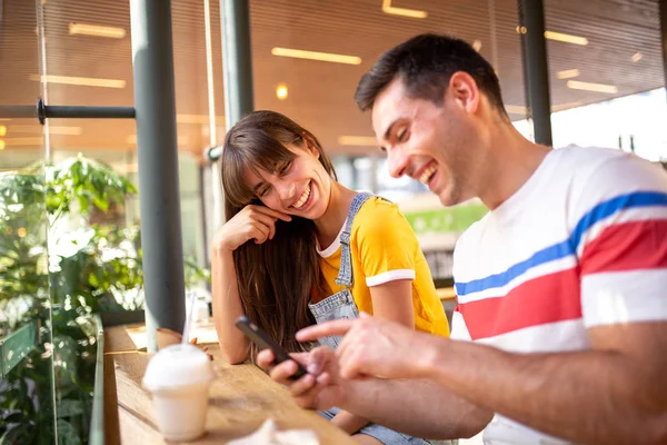 旁边的肖像画男友和女朋友坐在咖啡店里 一起看手机 — 图库照片