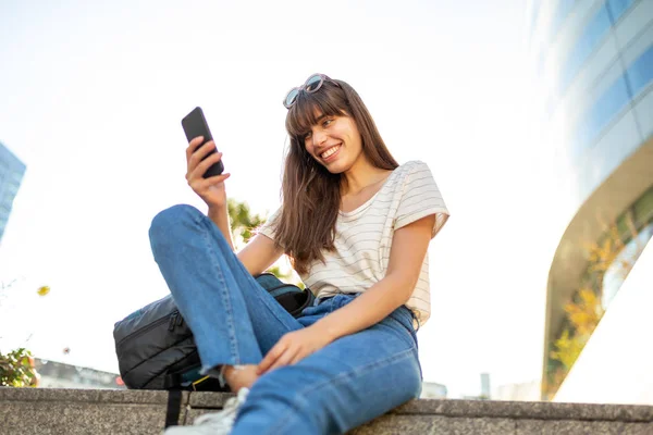 Портрет Молодой Женщины Сидящей Снаружи Смотрящей Мобильный Телефон — стоковое фото