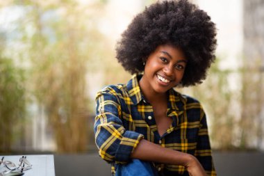 Afro saçlı, gülümseyen siyah bir kadının yakın portresi.