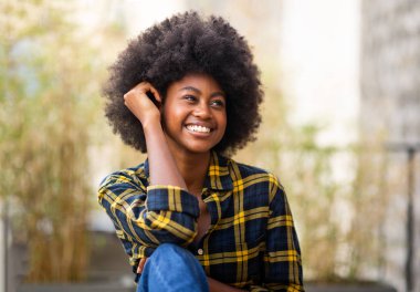 Çekici, gülümseyen, siyah saçlı bir kadının yakın portresi.