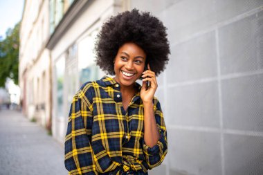 Sokakta telefonla konuşan genç siyahi bir kadının portresi.