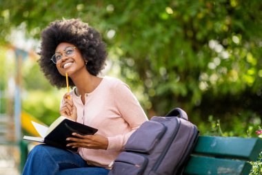 Bayan üniversite öğrencisinin portresi dışarıda çanta ve kitapla düşünüyor. 