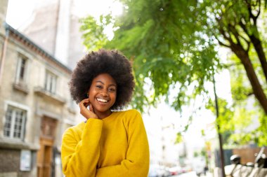 Dışarıda duran gülümseyen Afro-Amerikan kadının portresi.
