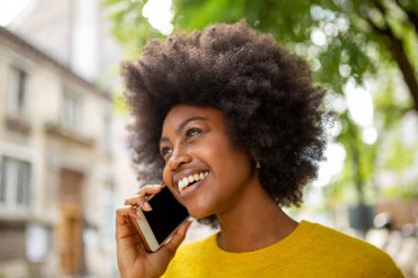 Çekici Afrikalı genç bir kadının cep telefonuyla gülümseyen ve konuşan portresini yakından çek.