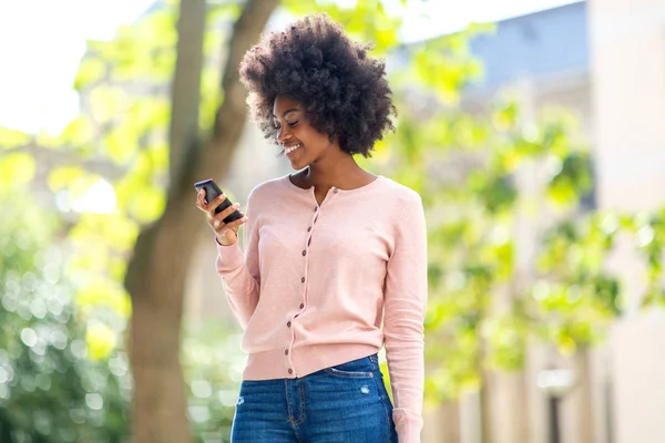 Retrato Una Hermosa Mujer Negra Sonriente Mirando Teléfono Móvil Afuera — Foto de Stock