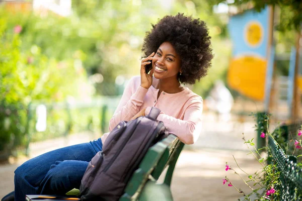 Πορτρέτο Χαμογελαστή Νεαρή Μαύρη Γυναίκα Κάθεται Στο Παγκάκι Μιλώντας Κινητό — Φωτογραφία Αρχείου