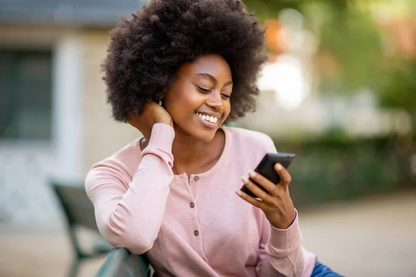 笑顔若いですアフリカ系アメリカ人女性とともにアフロ髪見ます携帯電話 — ストック写真