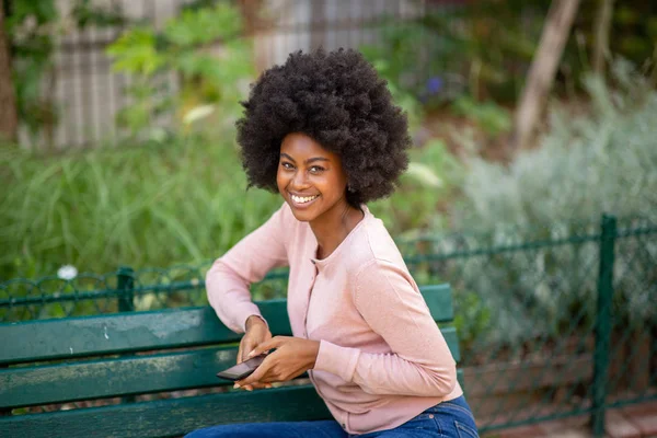 Retrato Jovem Afro Americana Sentada Banco Parque Com Telefone Mão — Fotografia de Stock