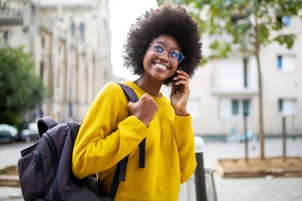 笑顔の若いアフリカ系アメリカ人女性の肖像とともに携帯電話で街を歩く眼鏡 — ストック写真