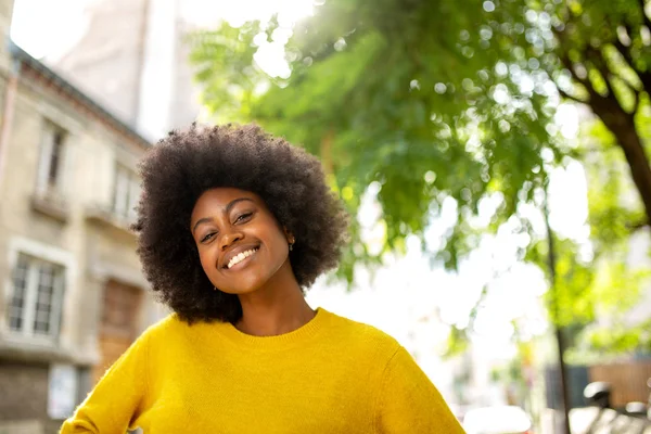 Portrait of happy black girl with afro smiling outside in city